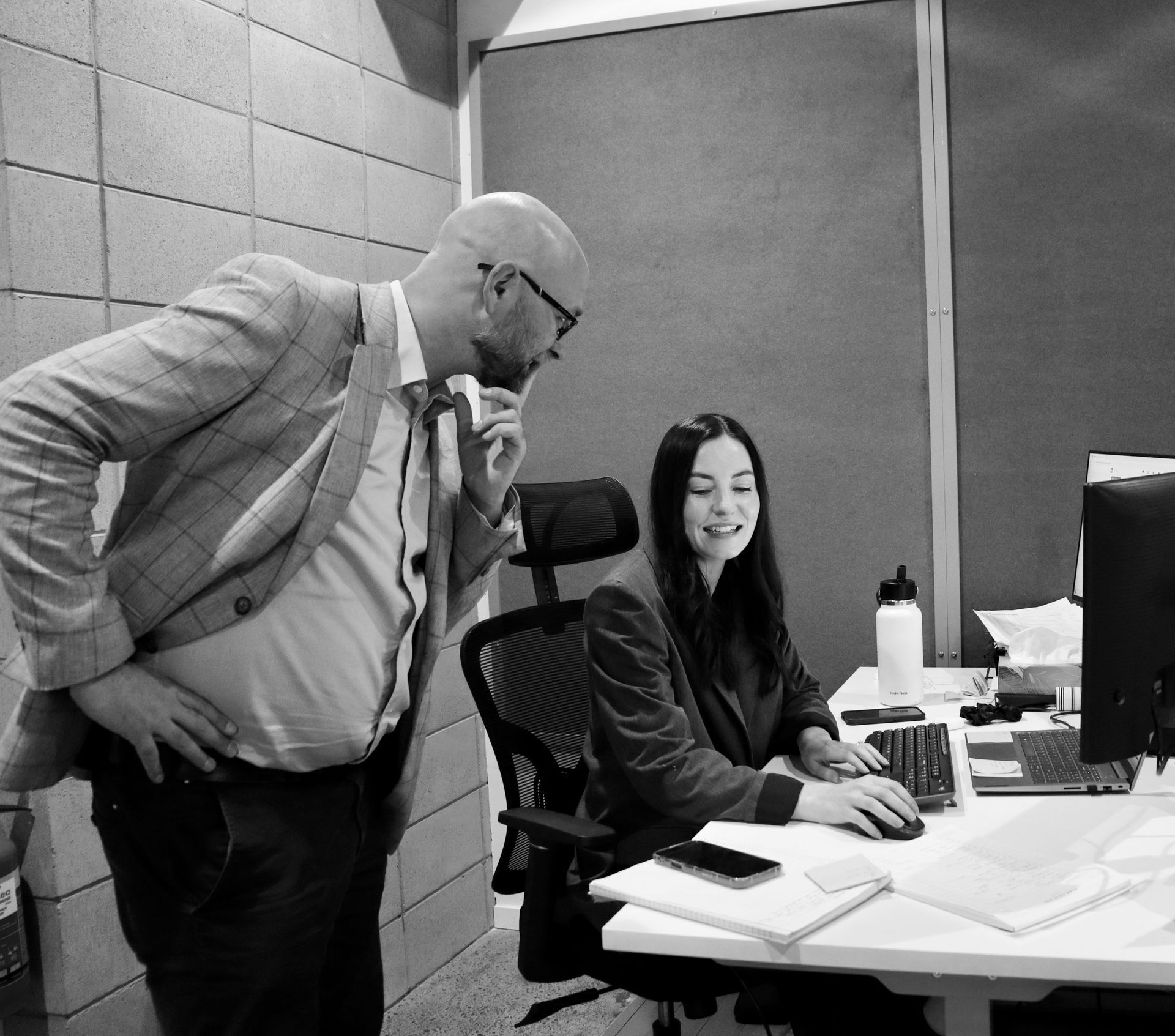 Two people in a meeting reviewing papers at a table with an open laptop.