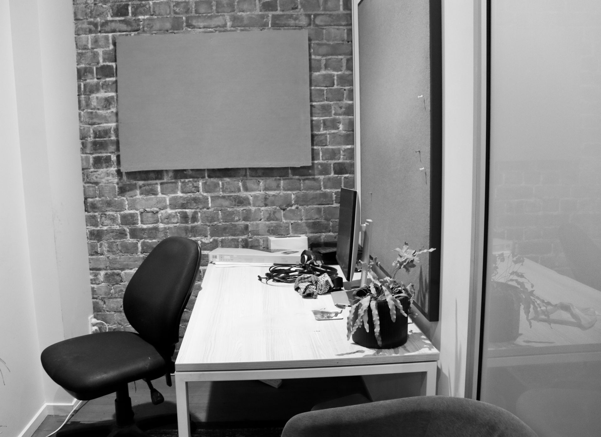 Empty office desk with chair, brick wall, and whiteboard