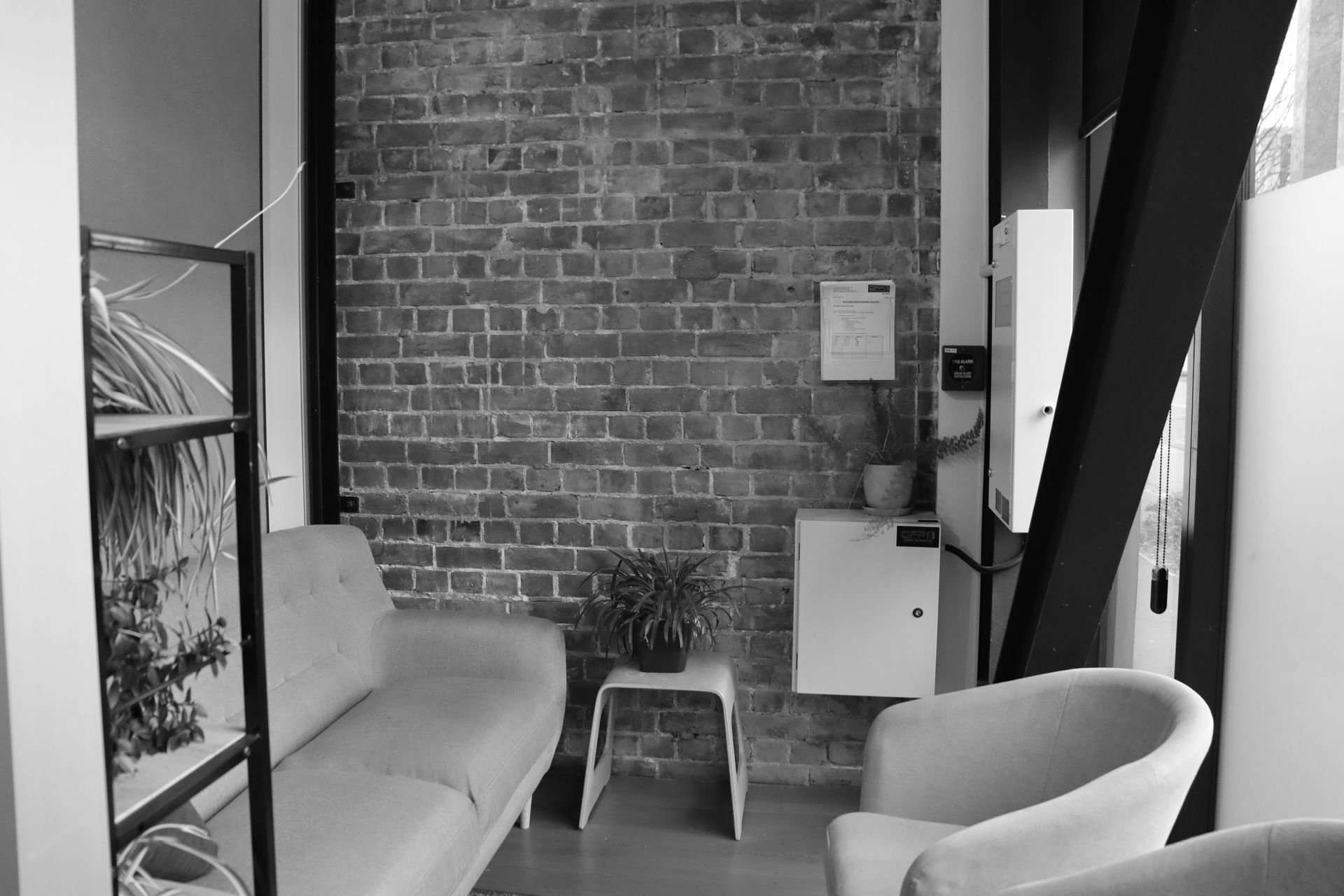 Cozy living room with brick wall, sofa, armchair, and small table in a narrow modern space