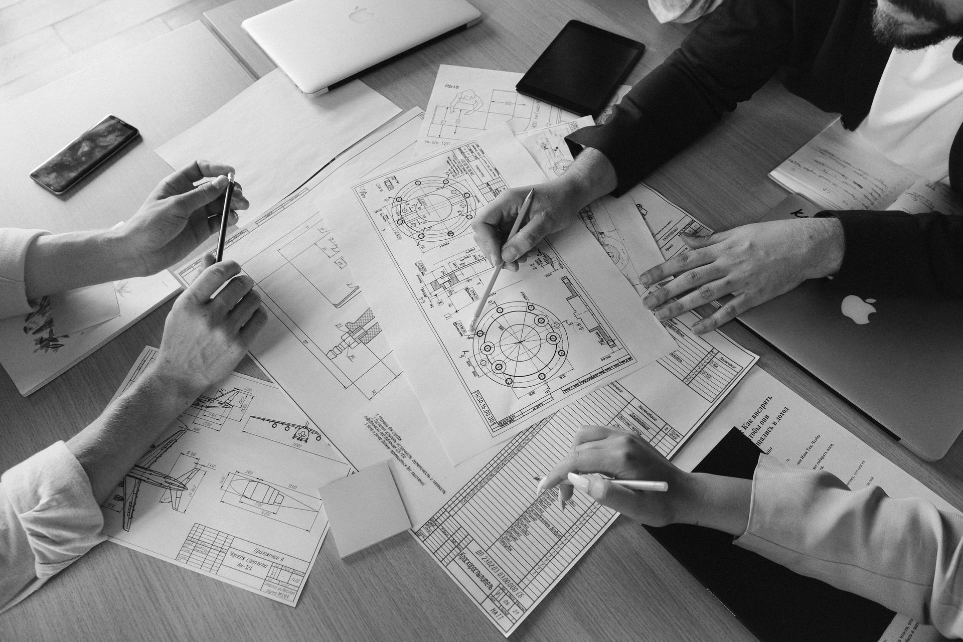 People reviewing architectural blueprints and drawings around a table