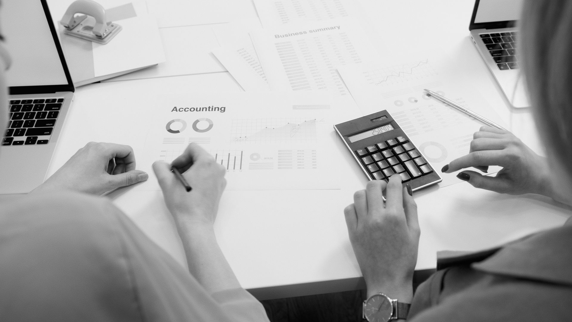 Two people reviewing finances at a desk with papers and a calculator