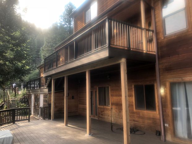 Wooden lodge with a covered porch and balcony beside trees in bright sunlight Wooden lodge with a covered porch and balcony beside trees in bright sunlight
