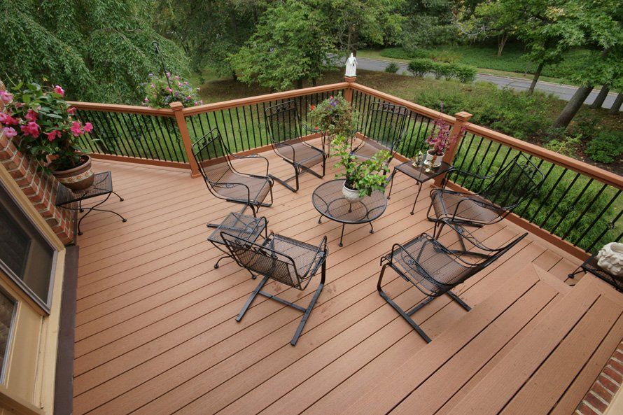 Wooden deck with patio furniture overlooking a lush green garden and path Wooden deck with patio furniture overlooking a lush green garden and path