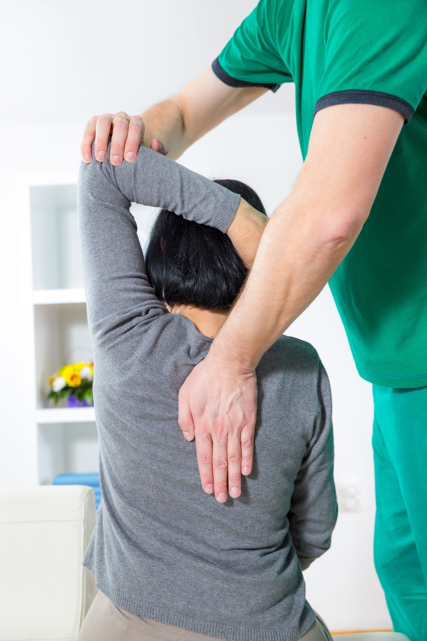 Un uomo allunga il braccio di una donna mentre lei è seduta su un divano.