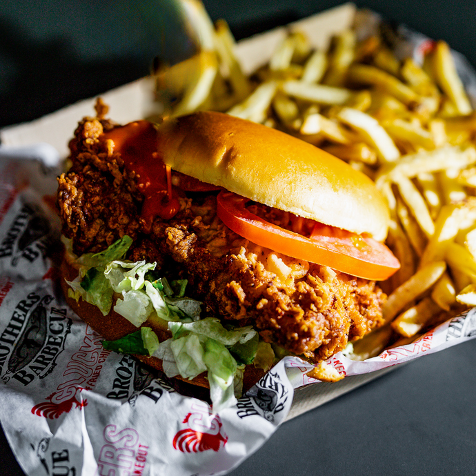 Close up of Clucker's Supreme sandwich with fries in the background.