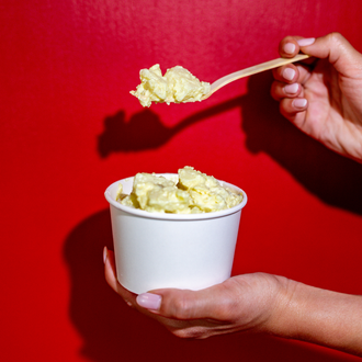 Potoato salad with microgreens and various spices on top all in a black serving dish. 