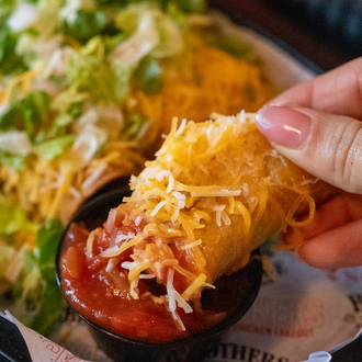 A close up of a Clucker's Cluckito being dipped in a sauce.