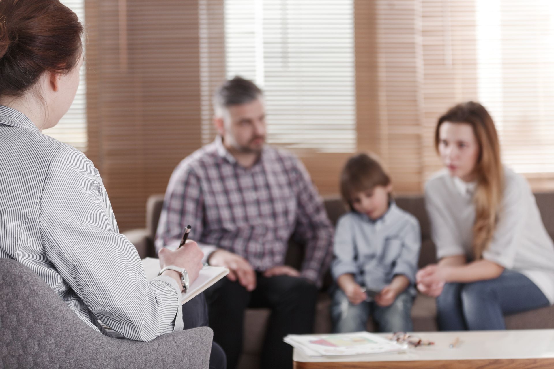 A family is sitting on a couch talking to a female therapist.