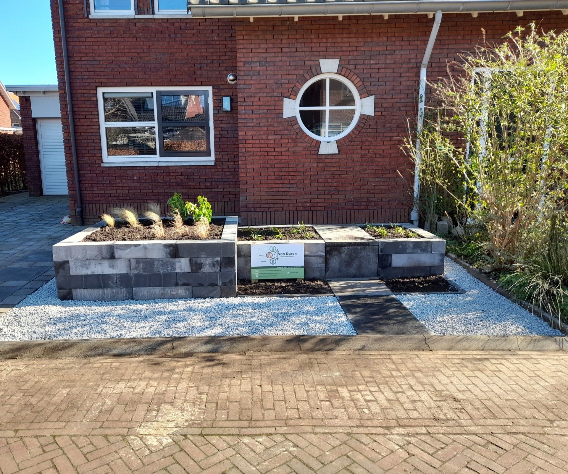 Een voortuin met bakstenen plantenbakken.