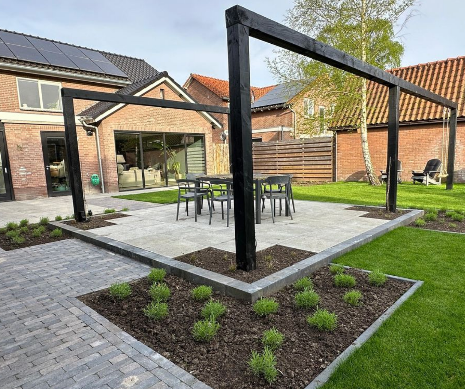 Er is een terras met een tafel en stoelen in de achtertuin van een huis.