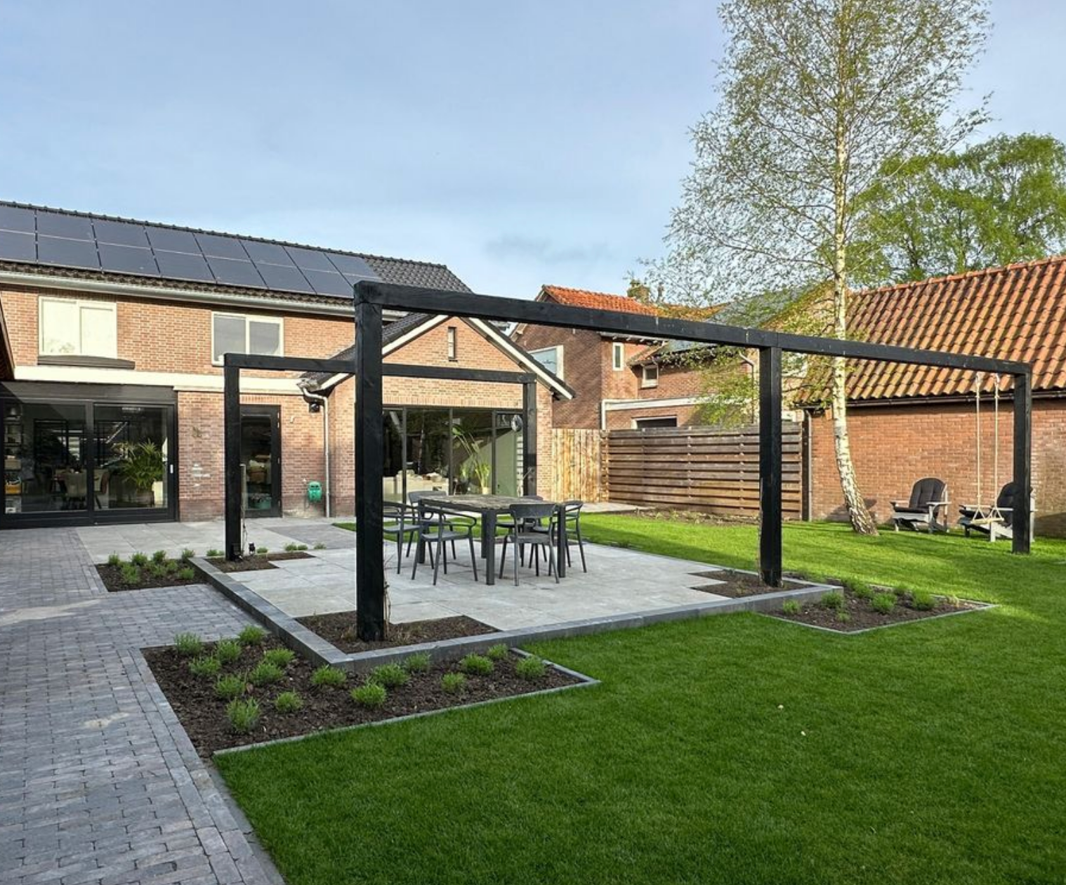 Er is een terras met een tafel en stoelen in de achtertuin van een huis.