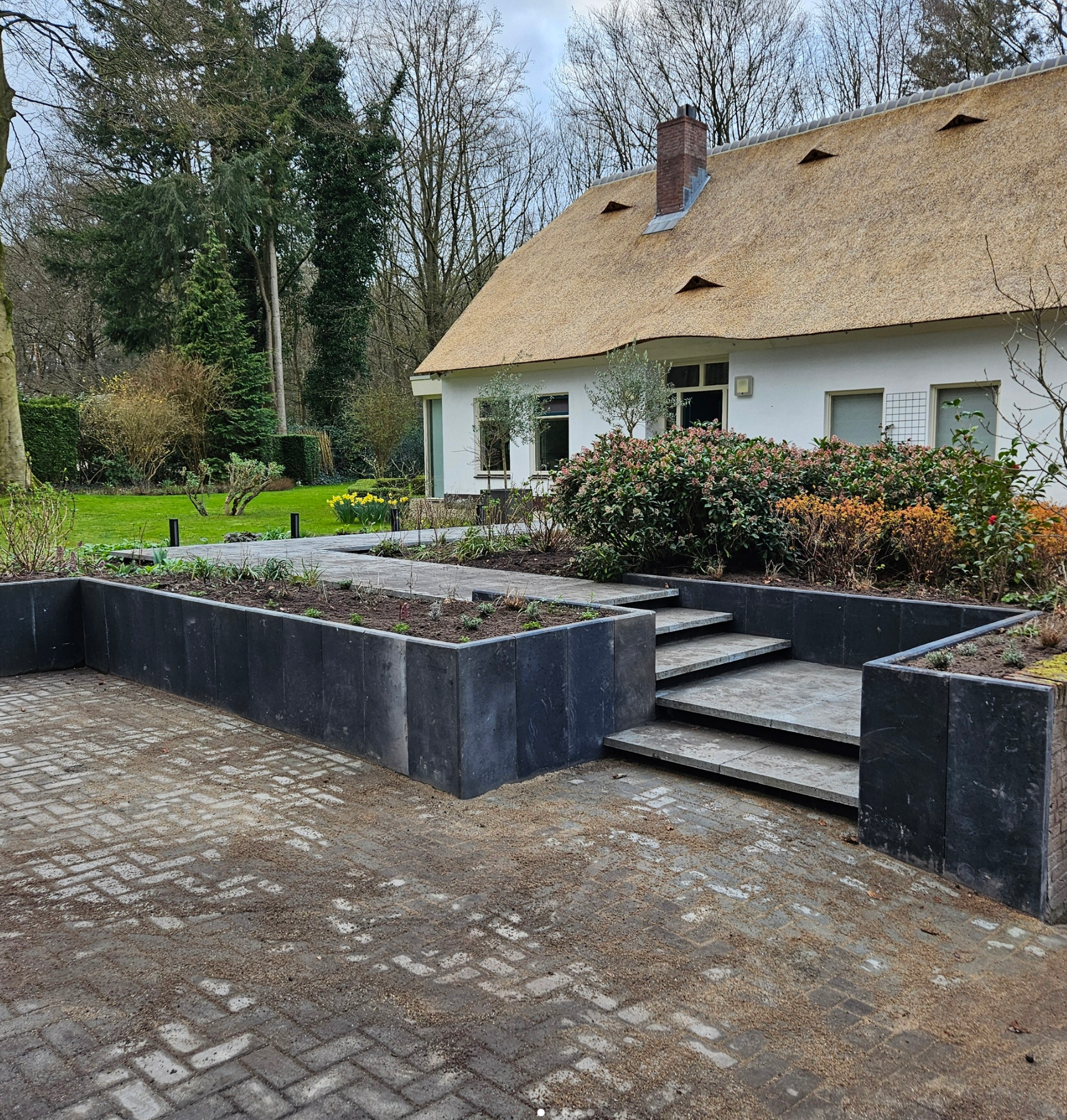 Een wit huis met een rieten dak en trappen die ernaartoe leiden