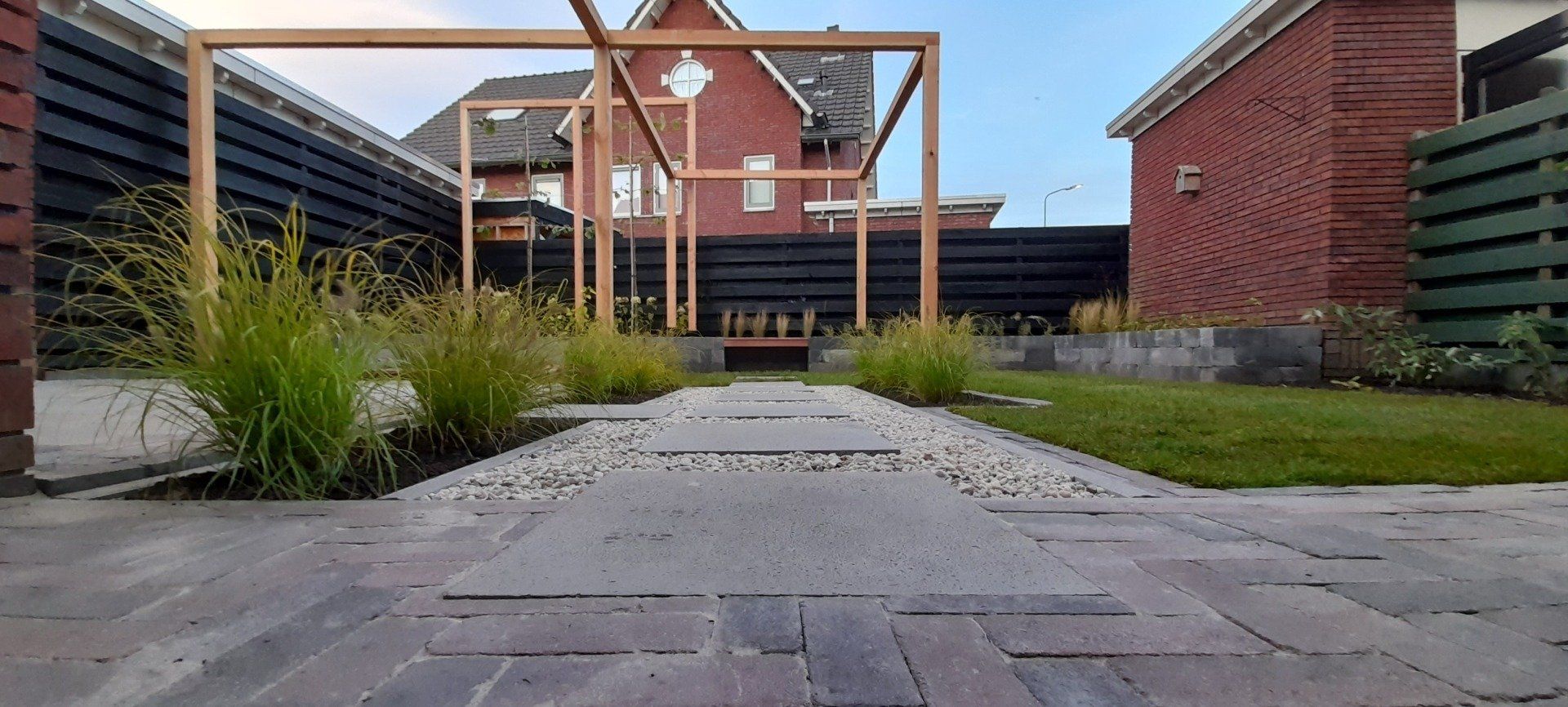 Een stenen pad met een houten pergola.