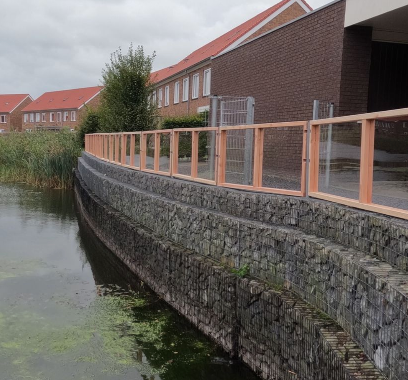 Een bakstenen huis met een transparante schutting ervoor.