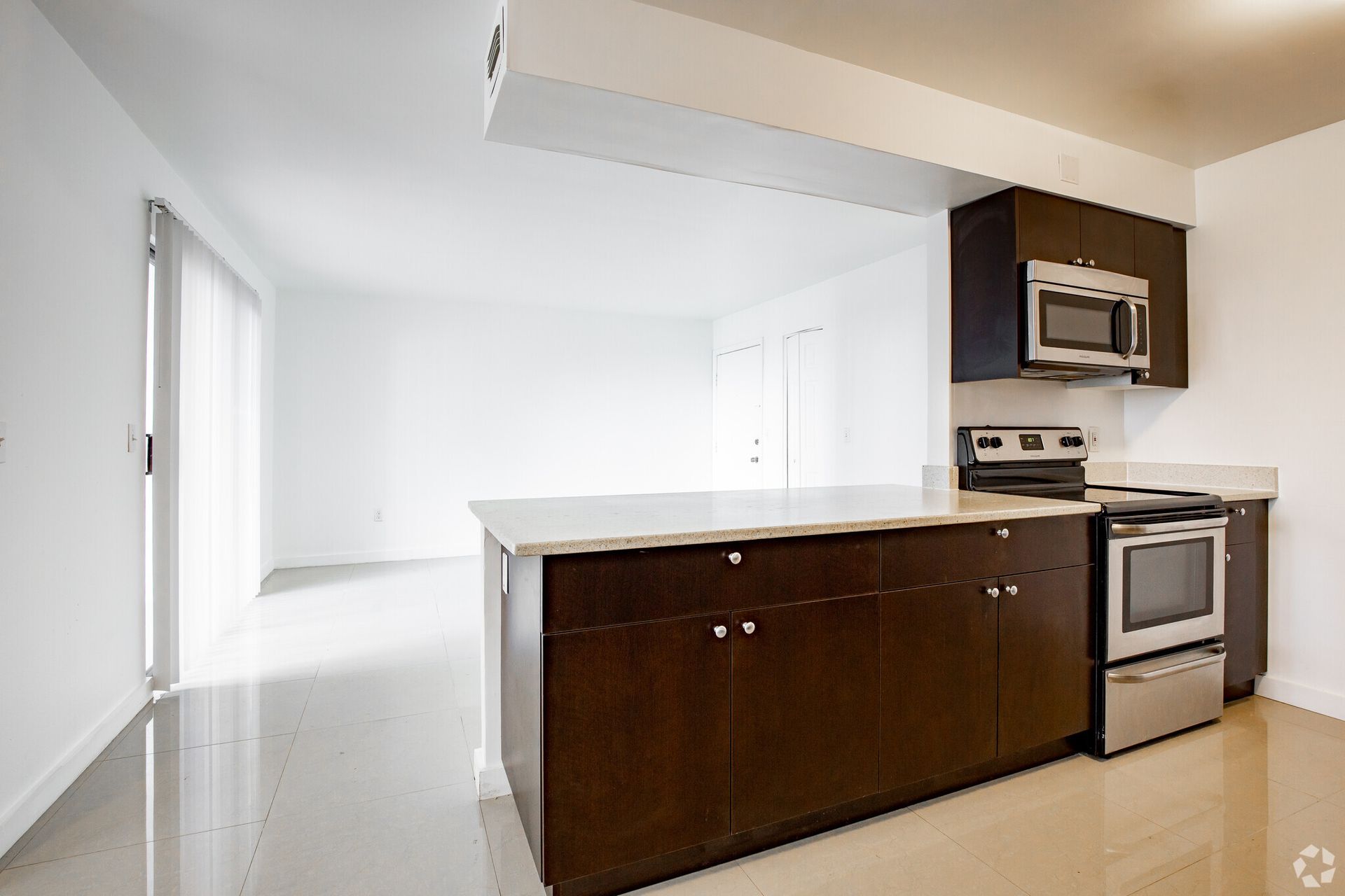 An empty kitchen with brown cabinets and stainless steel appliances