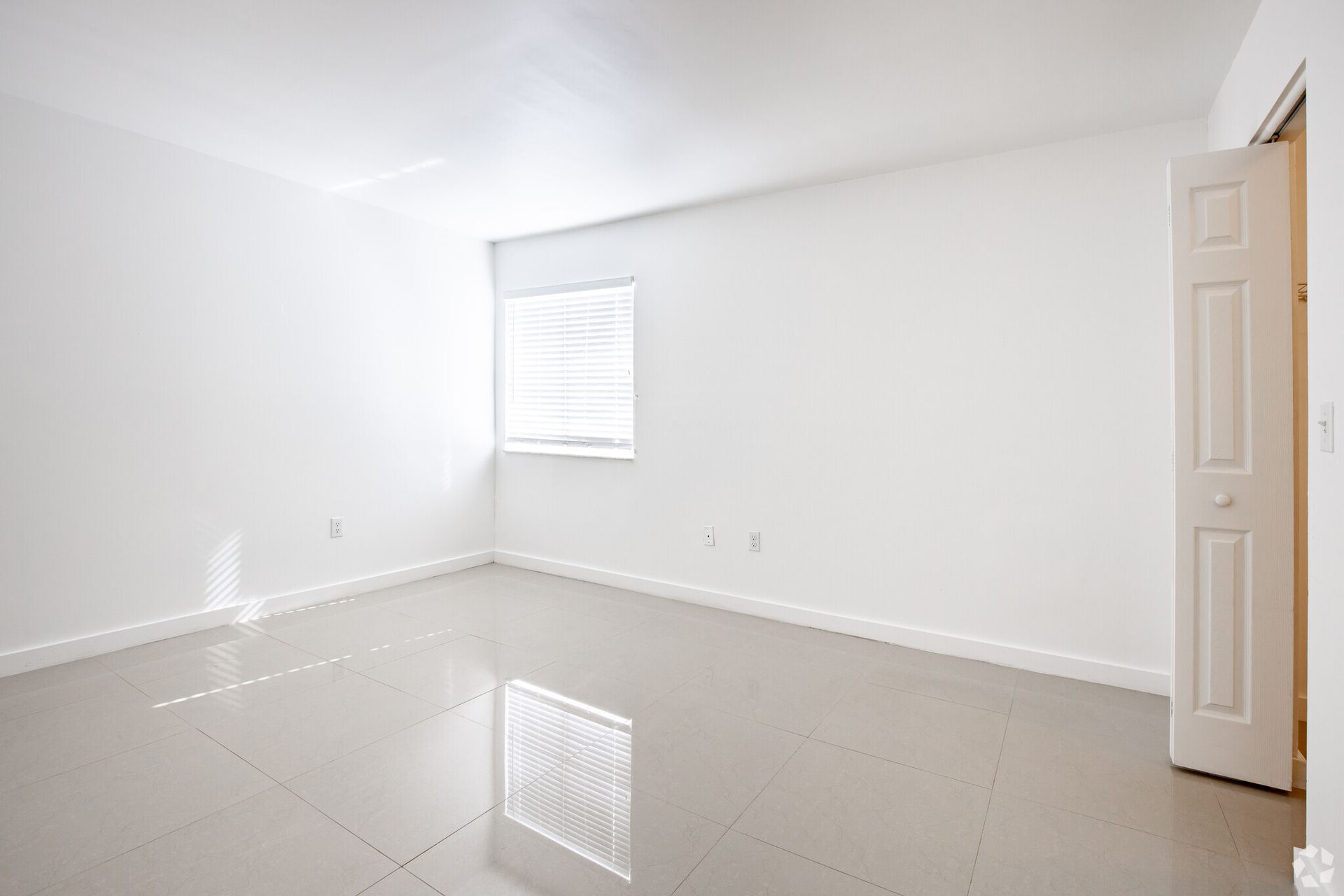 An empty room with white walls and a window.