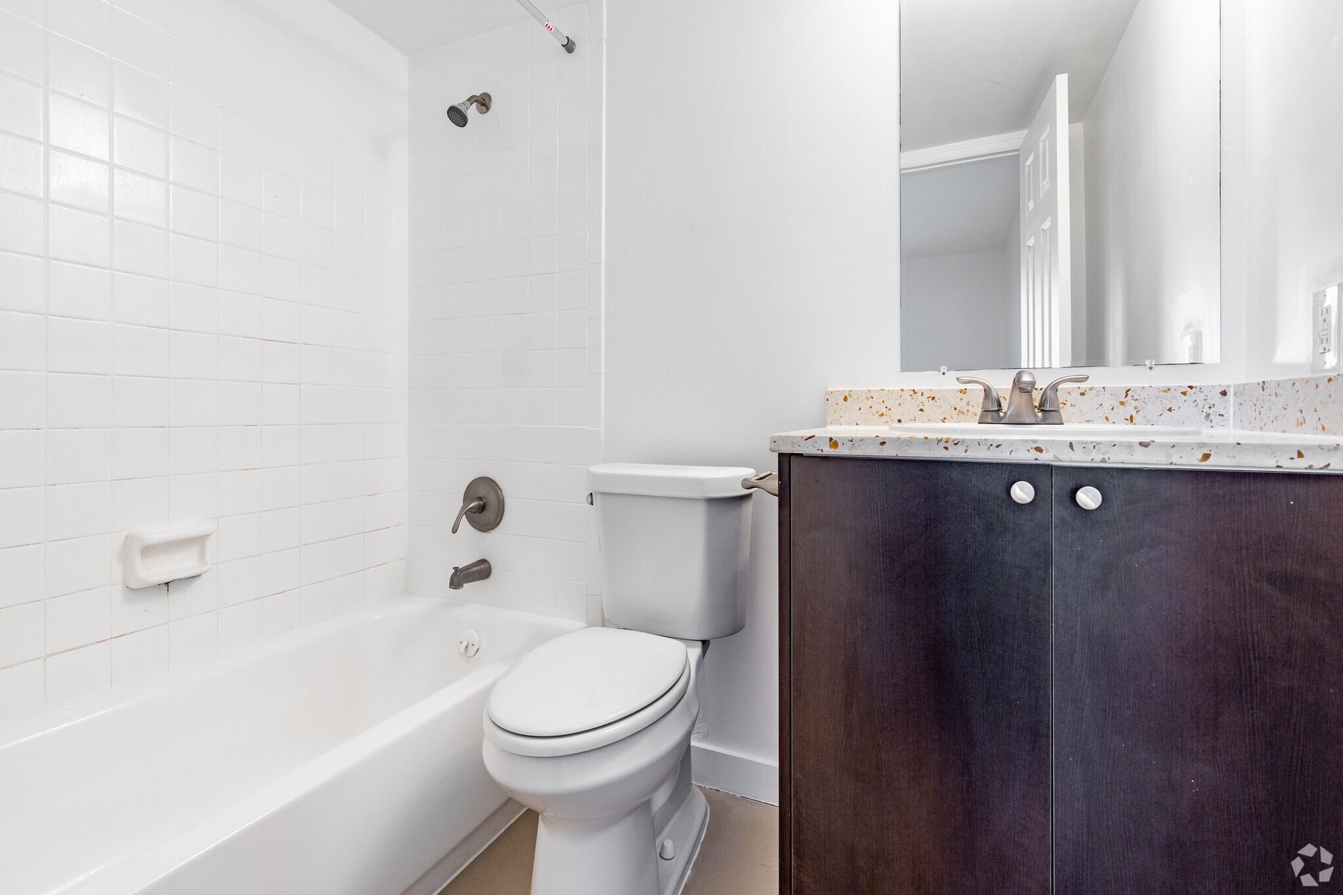 A bathroom with a toilet , bathtub , sink and mirror.