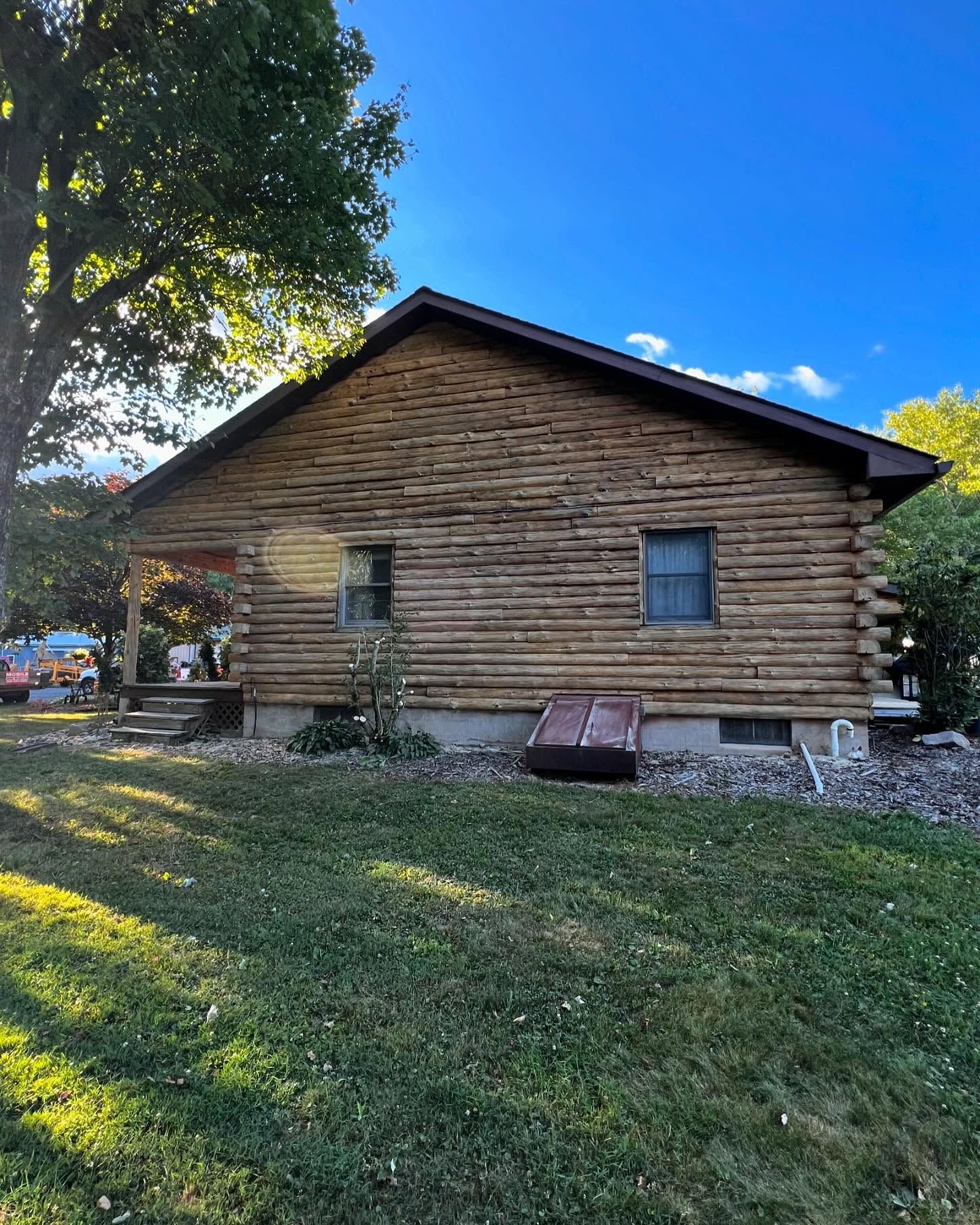 A log cabin is sitting in the middle of a lush green field.