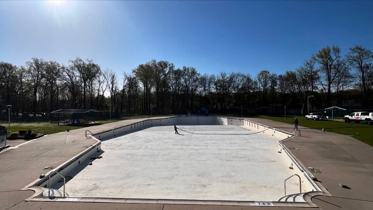 An empty swimming pool with trees in the background on a sunny day.