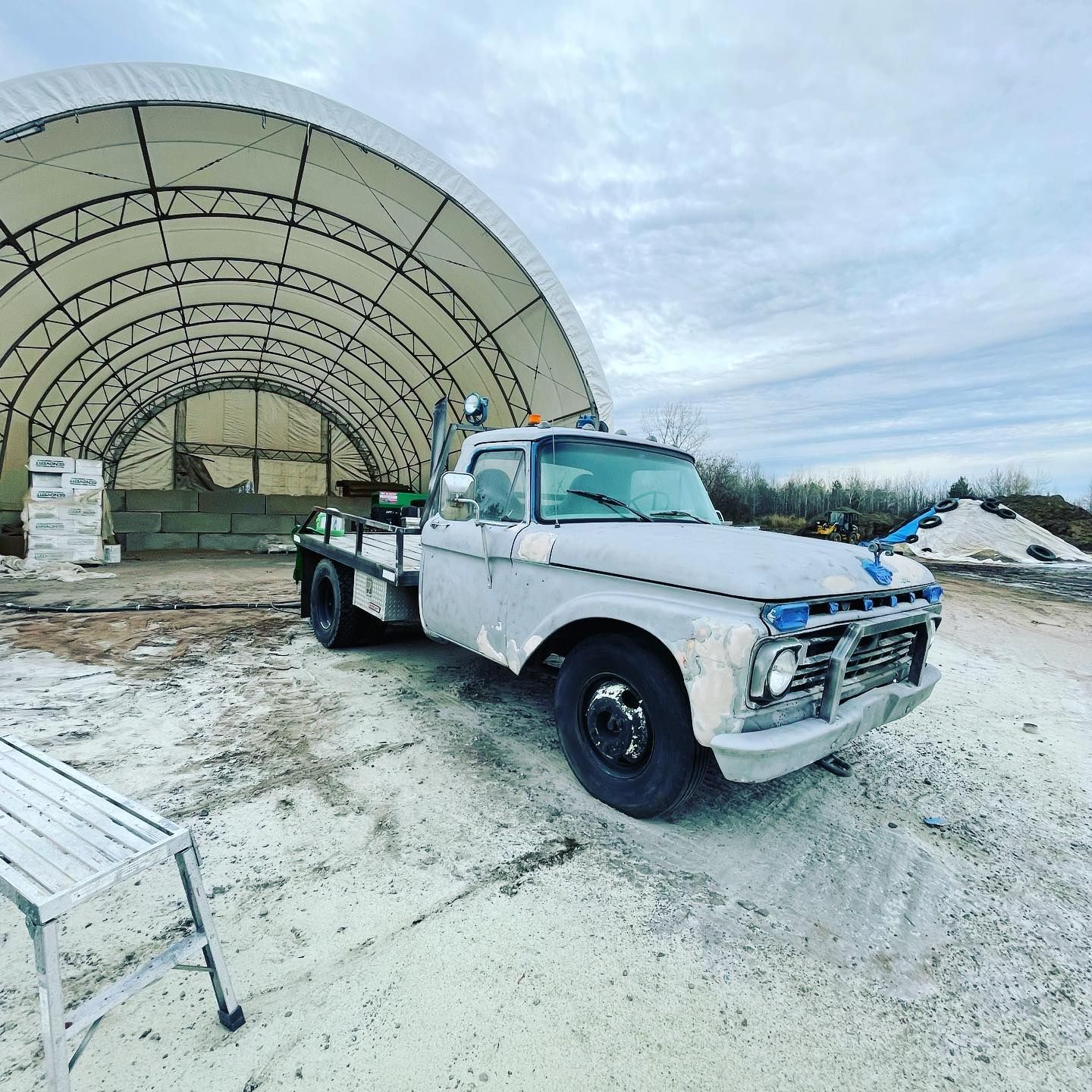 A white truck is parked in front of a large tent.