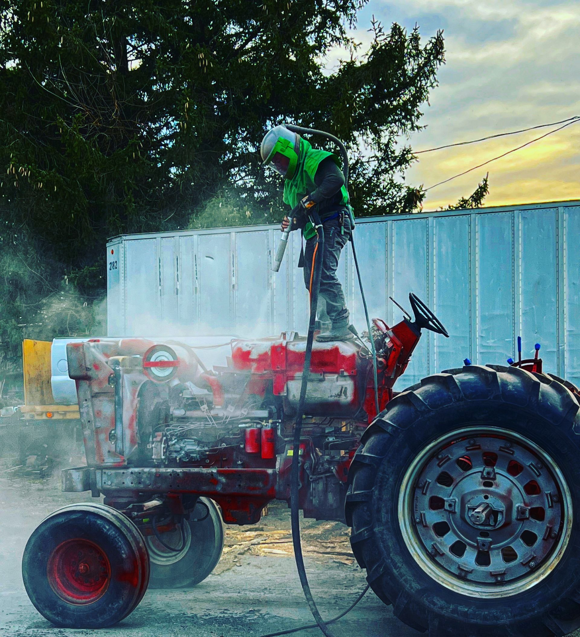 A man is cleaning a tractor with a high pressure washer