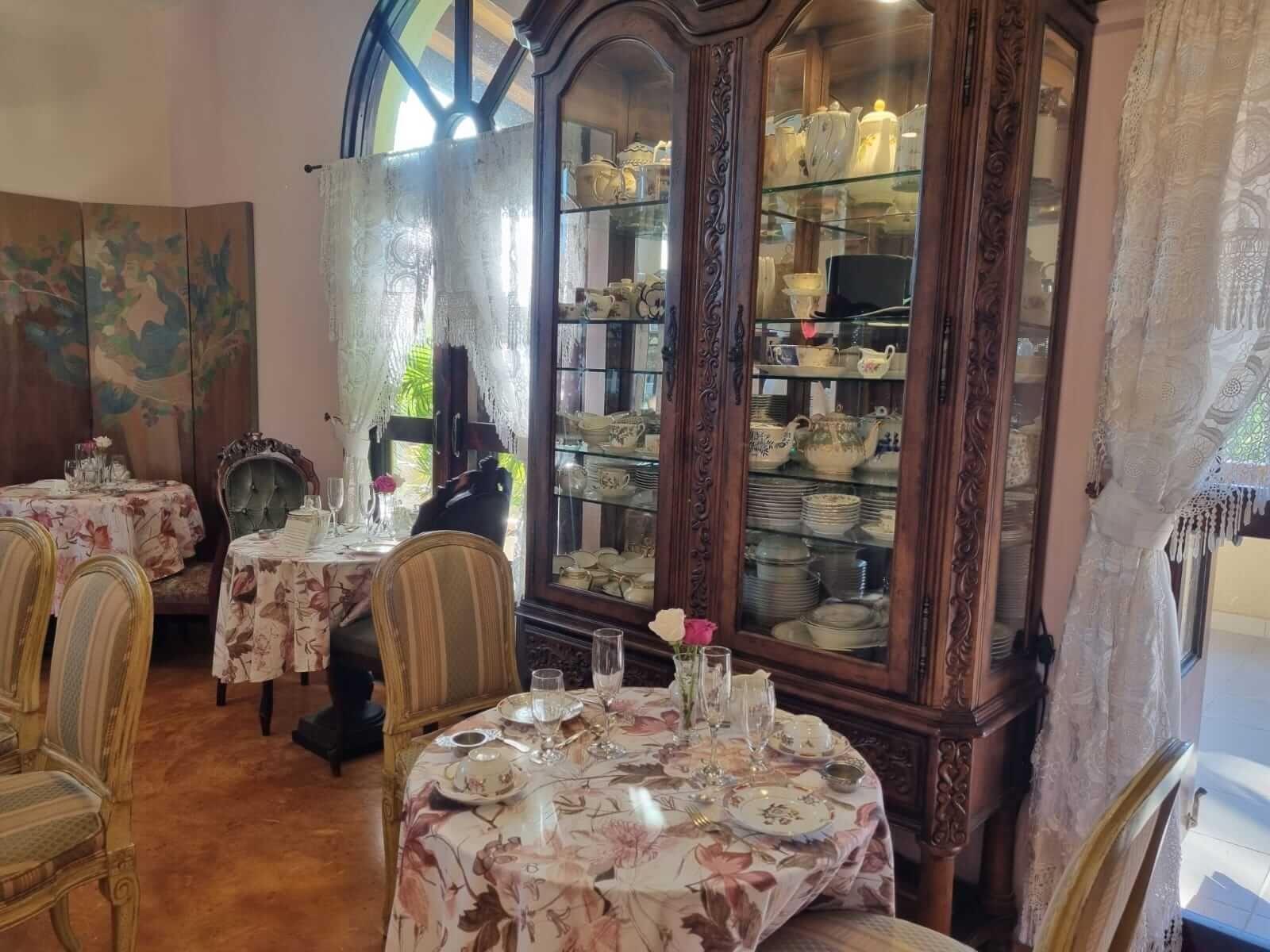 Un comedor con mesas y sillas y un aparador lleno de platos.