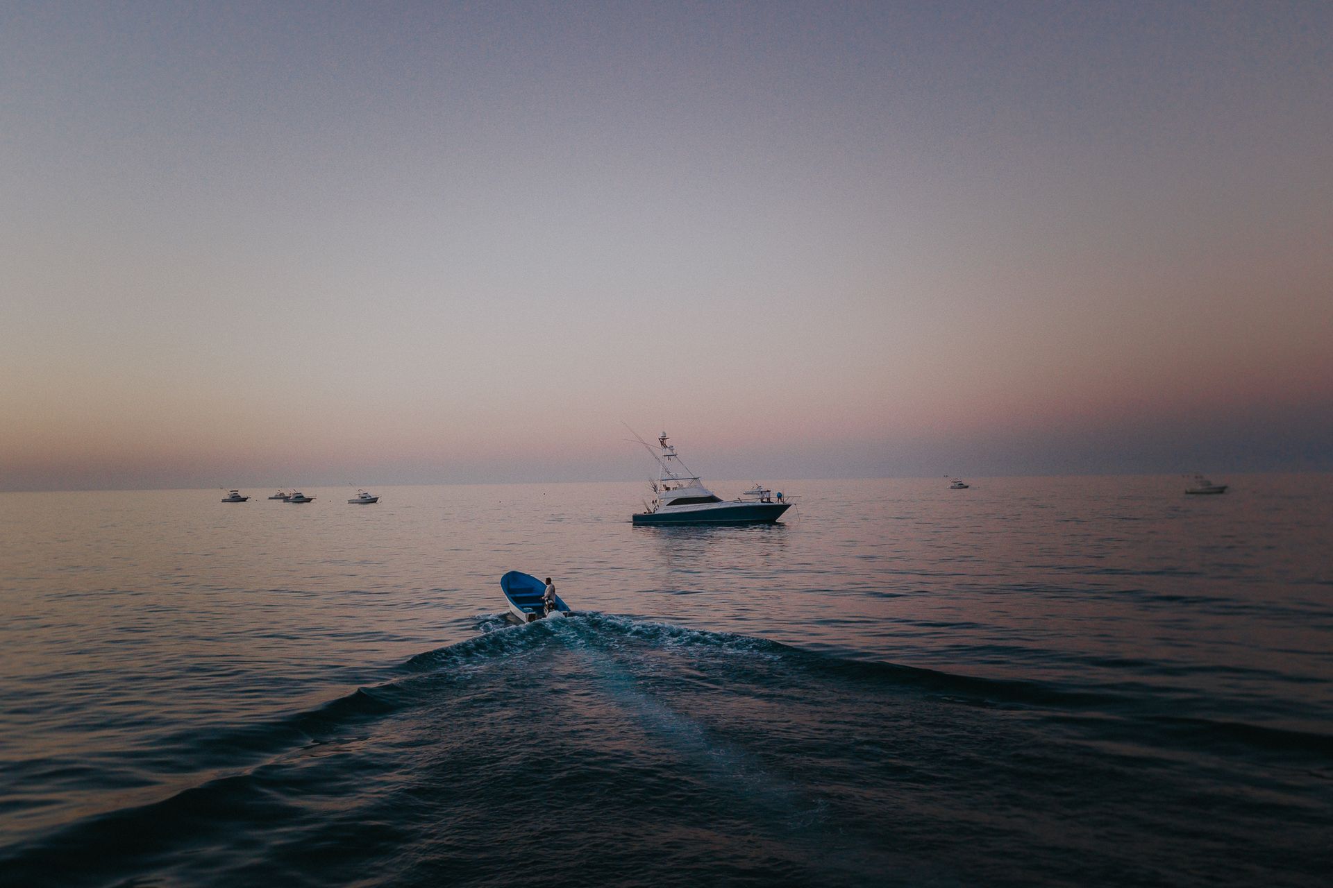 Un barco flota sobre un cuerpo de agua al atardecer.