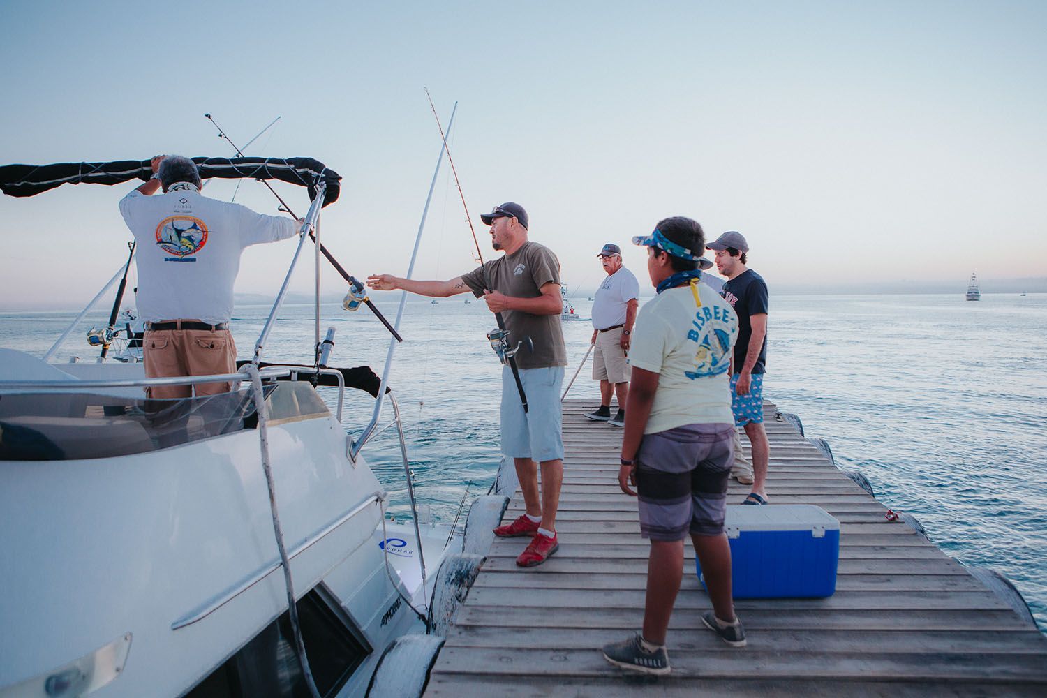 Un grupo de hombres está parado en un muelle junto a un barco.