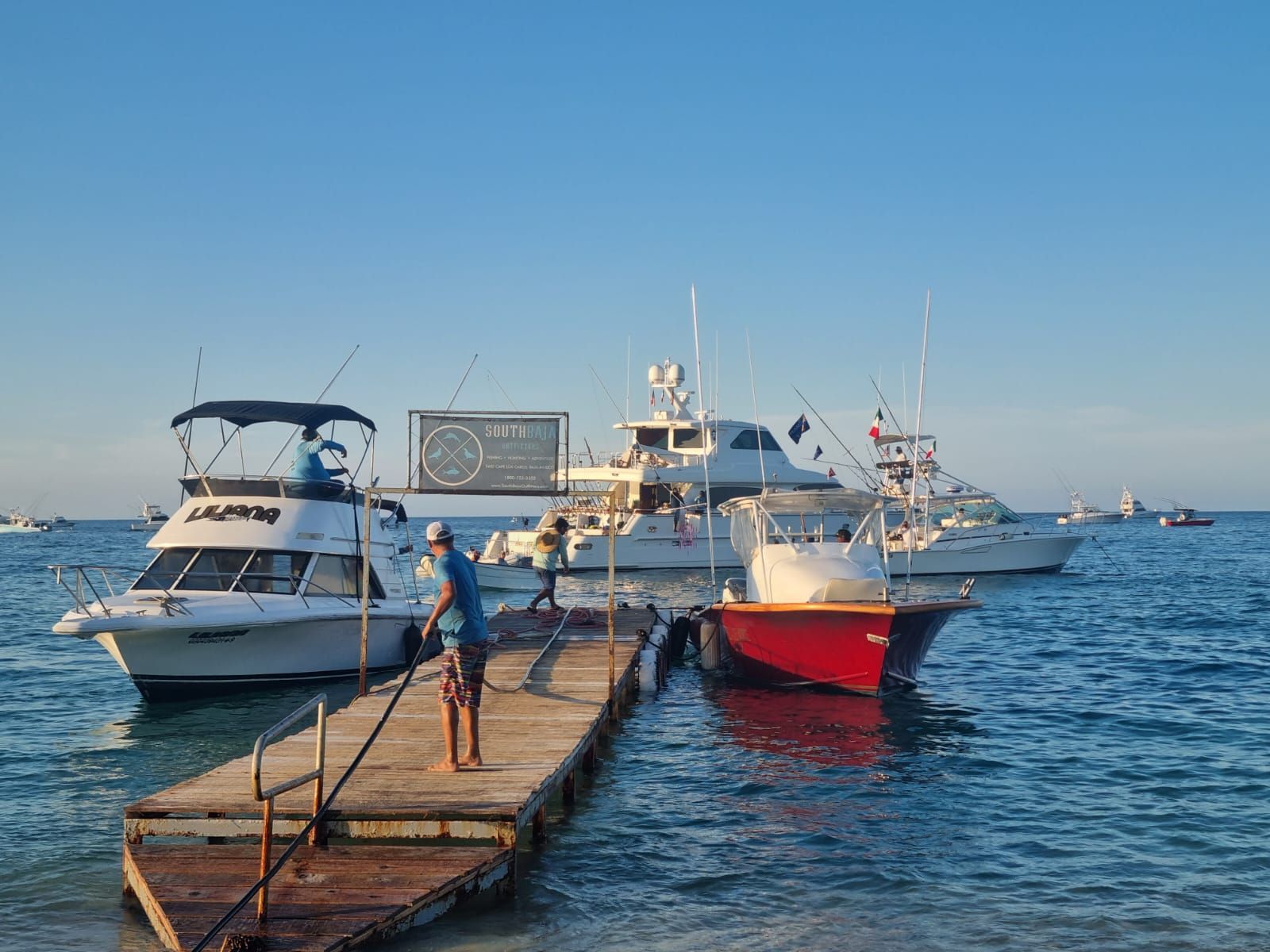 Un hombre está parado en un muelle junto a barcos en el agua.