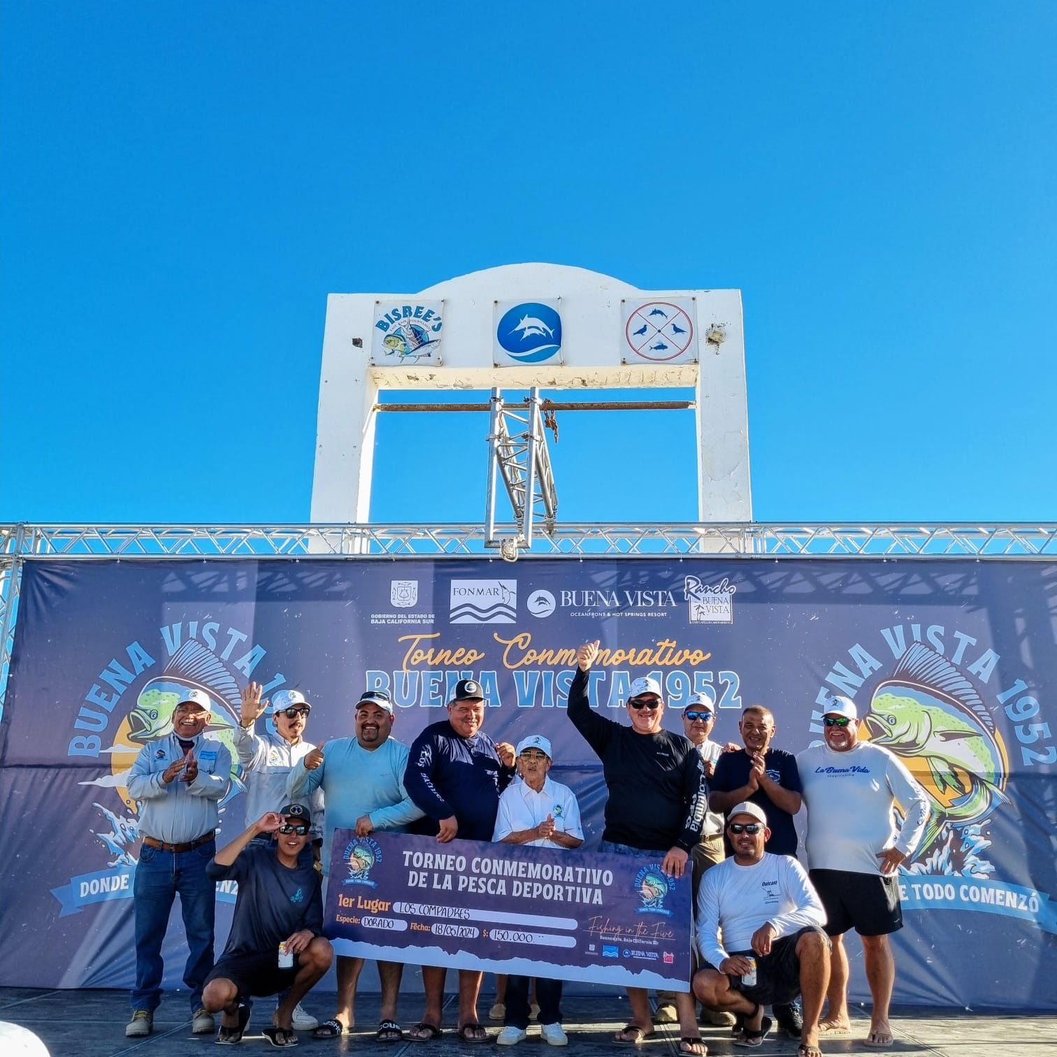 Un grupo de hombres parados frente a un cartel que dice buena vista