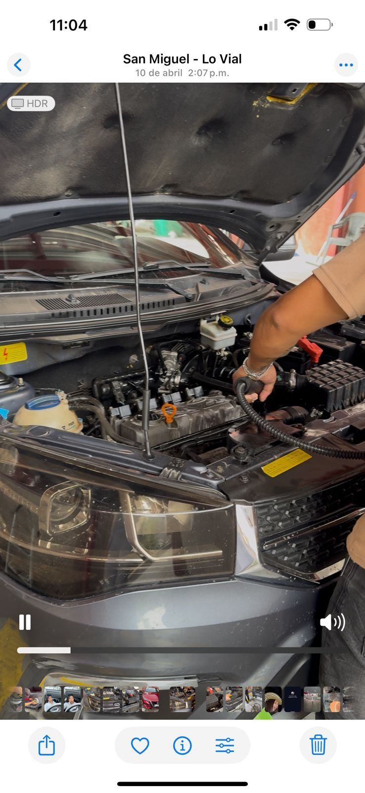 Una persona está mirando debajo del capó de un coche.