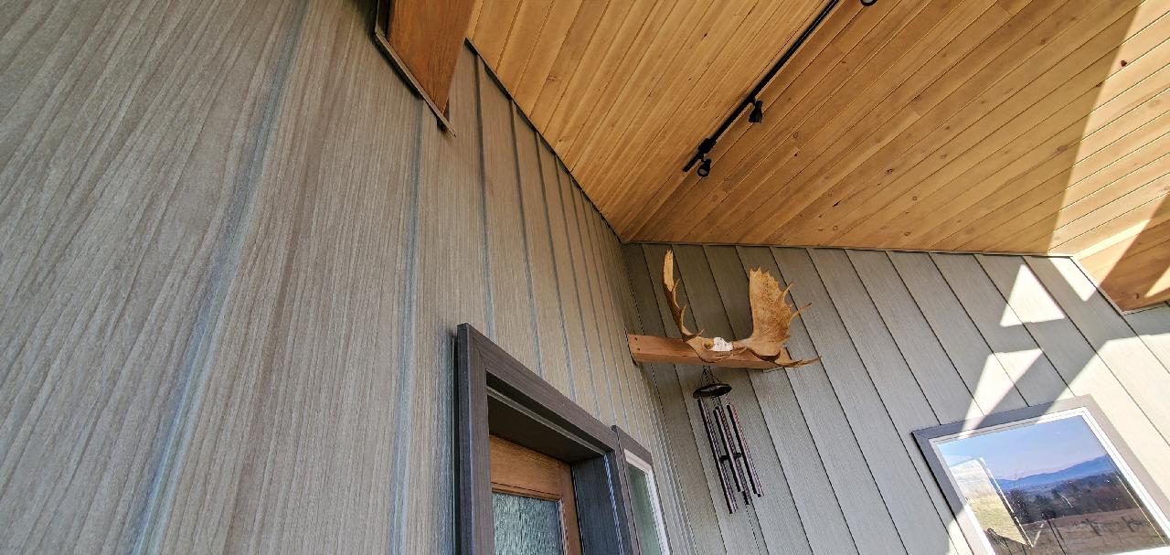 Exterior of a building with wood siding, a wooden ceiling, and a decorative antler mount.
