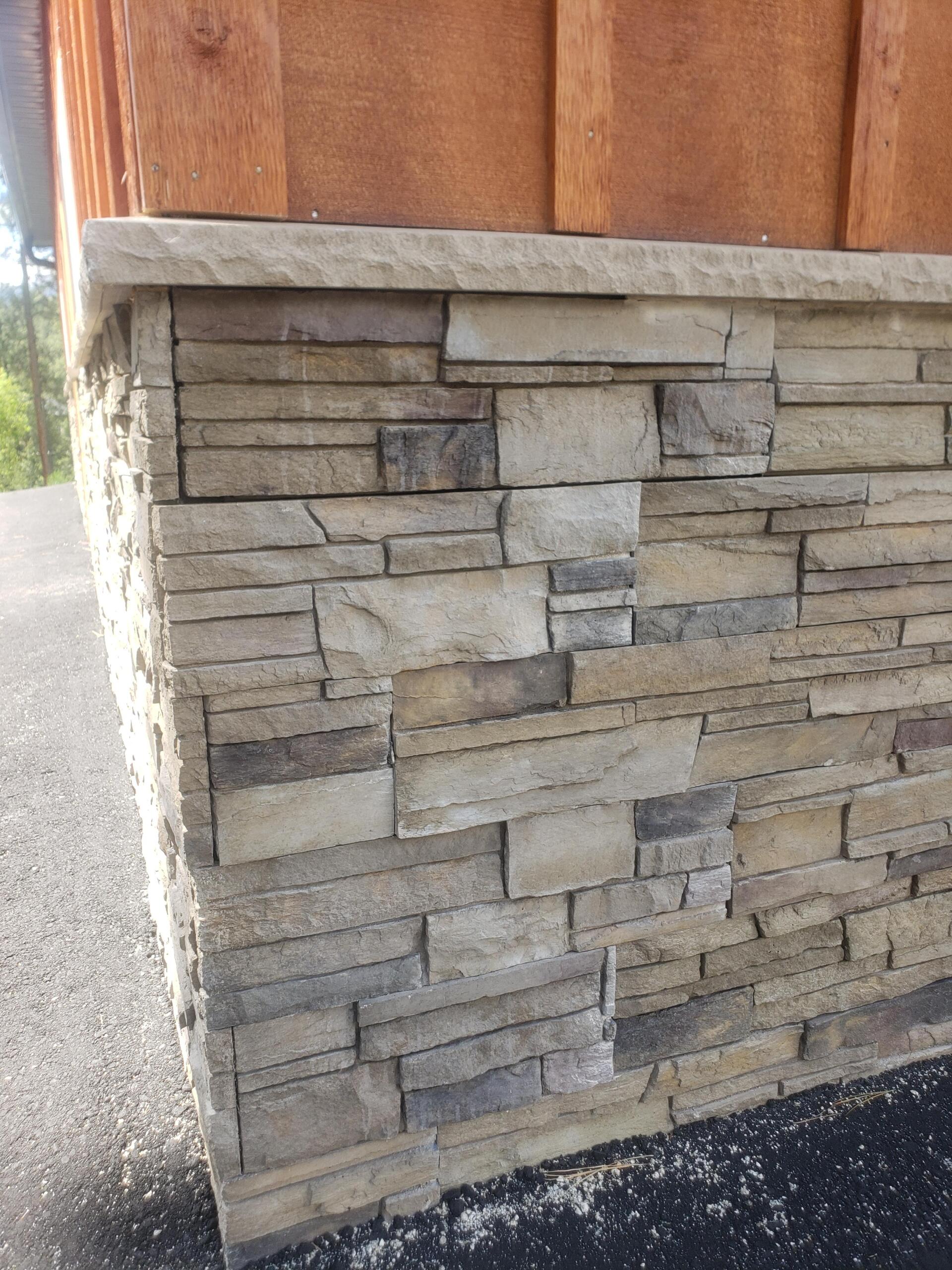 Stone veneer on building corner, tan and gray, with wooden siding above.