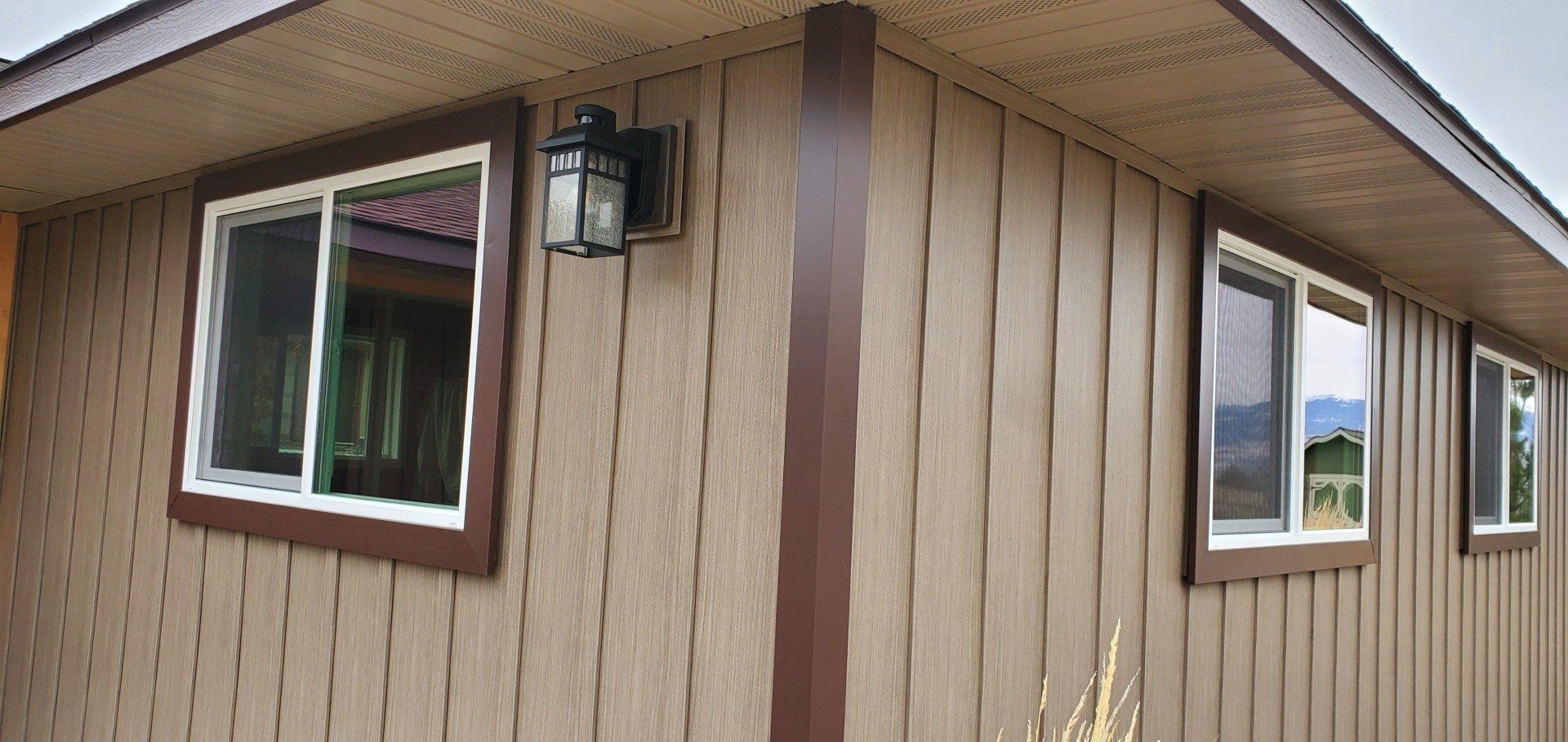 Exterior of a tan building with brown trim, windows, and a light fixture.