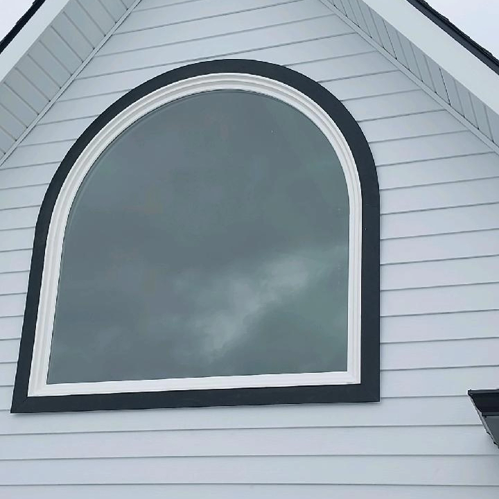 Large arched window on a white house, outlined with black and white trim.
