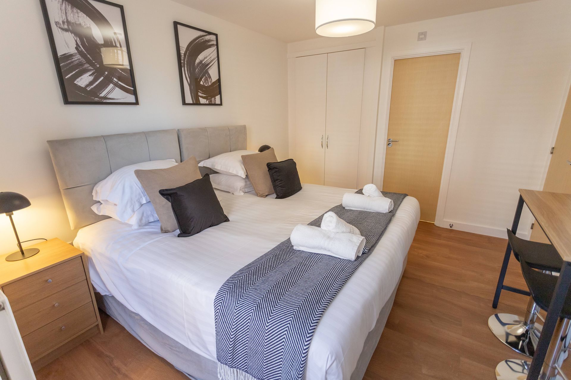 This image shows the master bedroom at Bedford Meadows apartment. It has a grey bedhead and fresh linen.