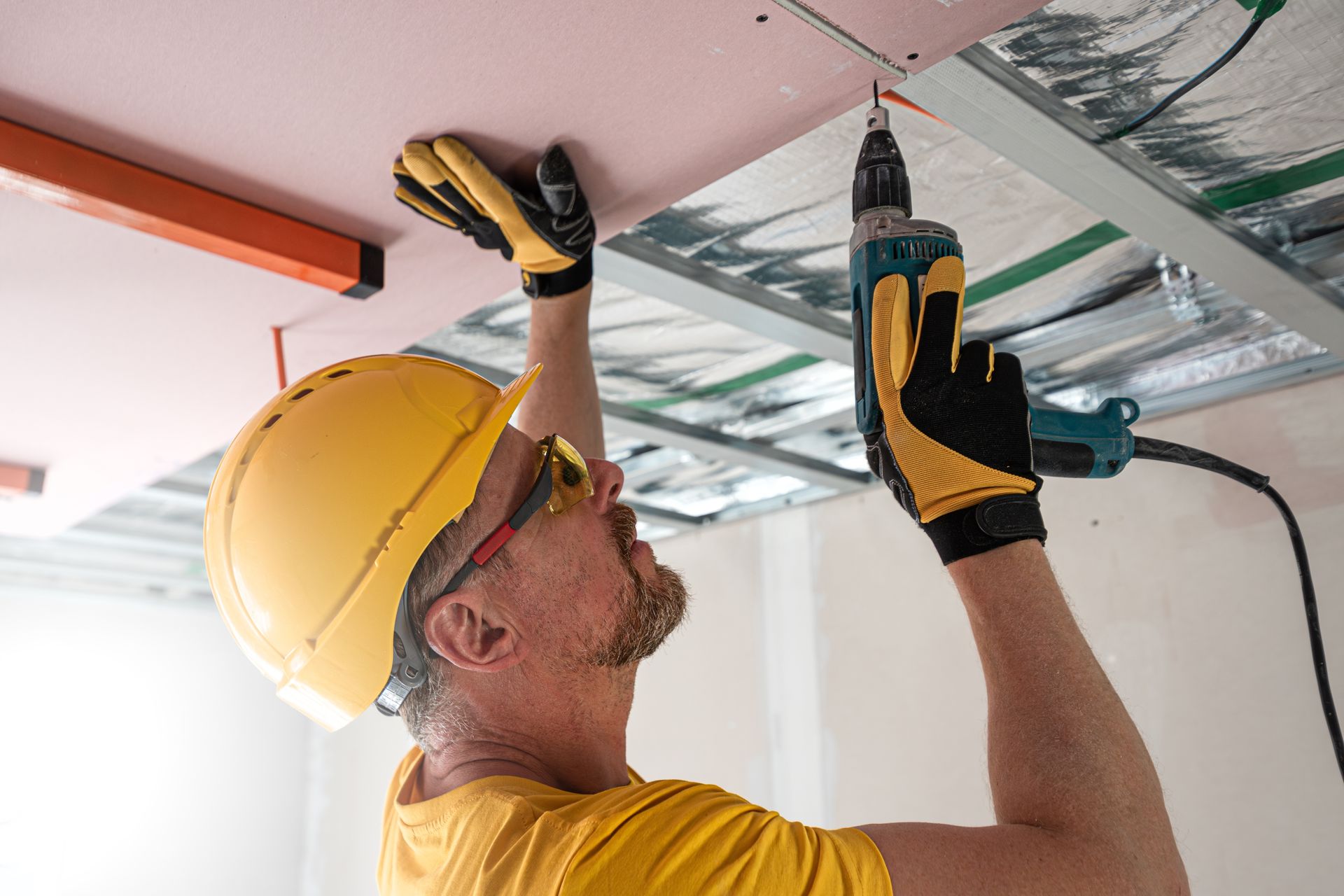 A man is working on a ceiling with a drill.