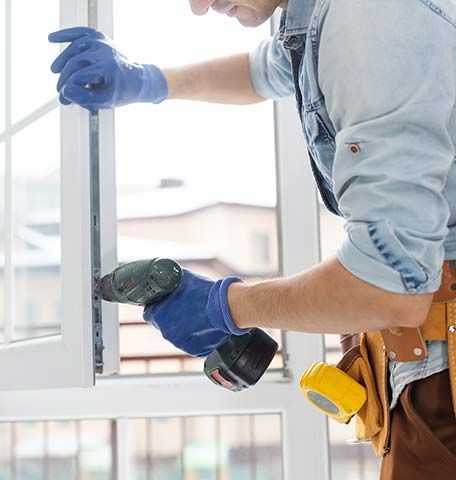 A man is using a drill to fix a window.