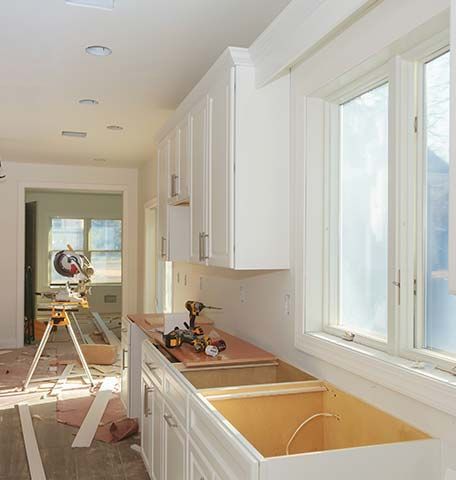 A kitchen under construction with white cabinets and a sink.