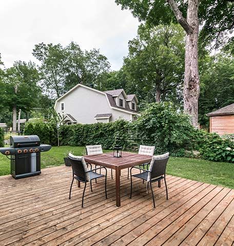 A wooden deck with a table and chairs and a grill.