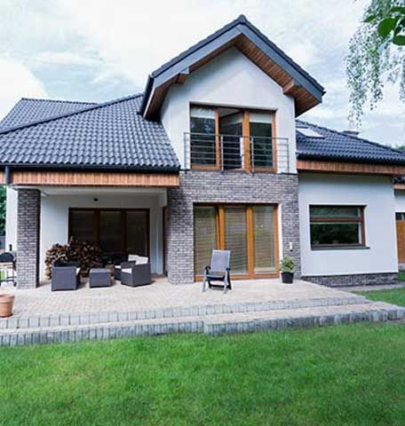 A large white house with a black roof and a patio in front of it.