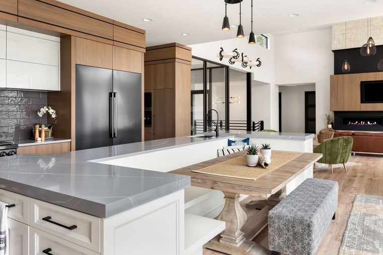 A kitchen with a large island , a table , and a refrigerator.