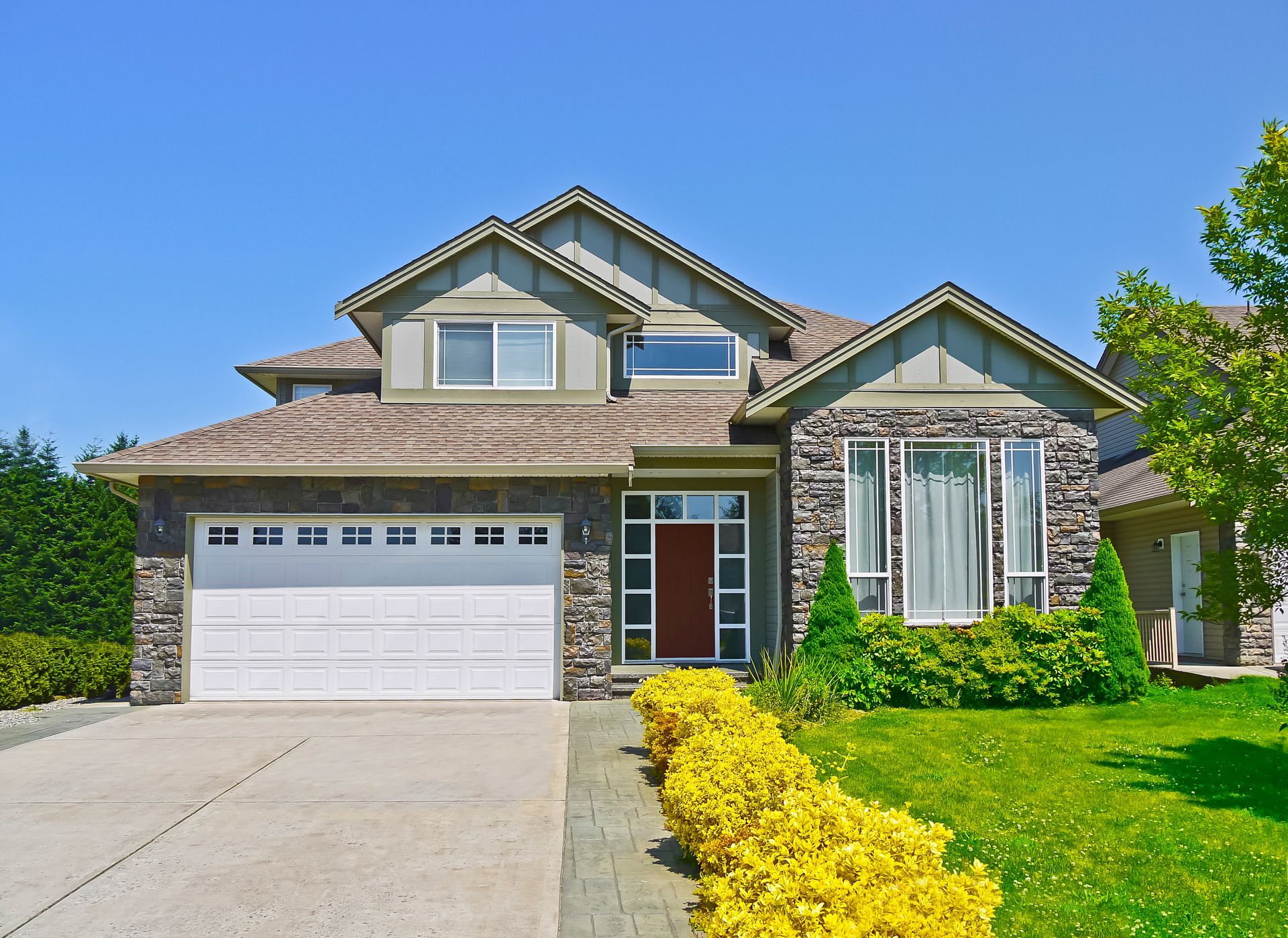 A large house with a white garage door and a red door