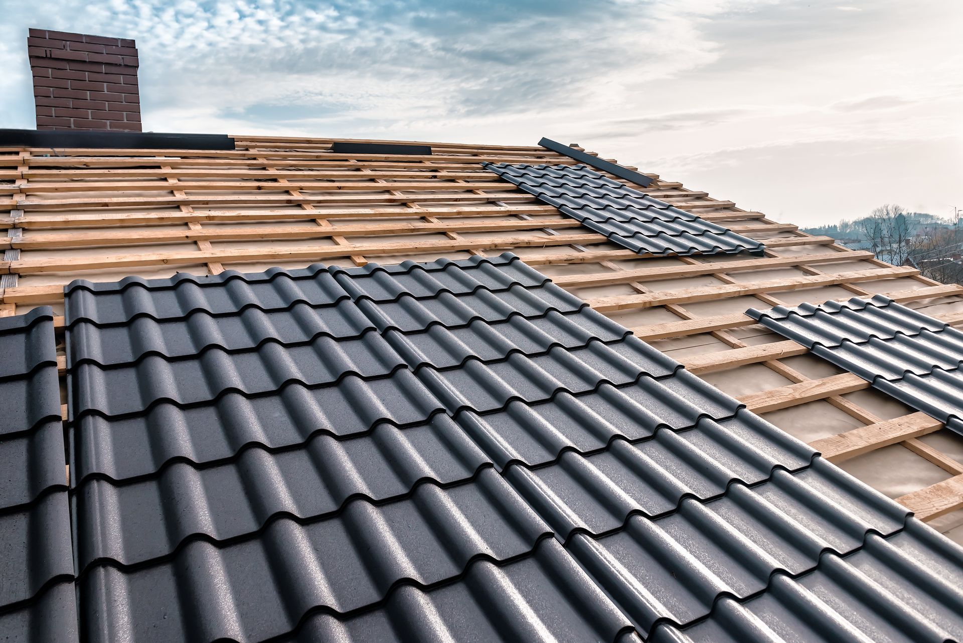 The roof of a house is being built and the tiles are being installed.