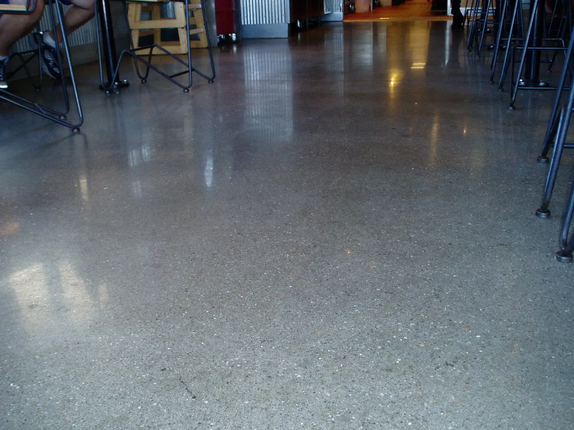 A shiny concrete floor in a restaurant with tables and chairs