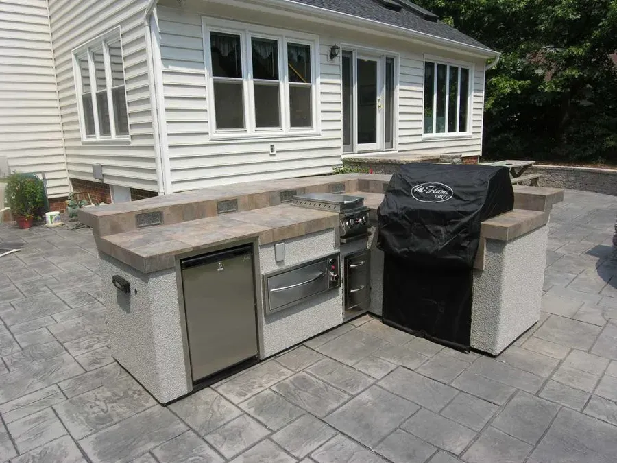 A grill is sitting on a patio in front of a house.