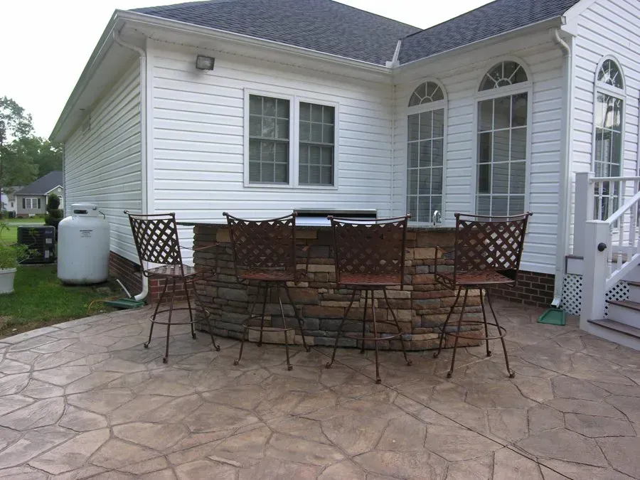 A patio with a table and chairs in front of a white house