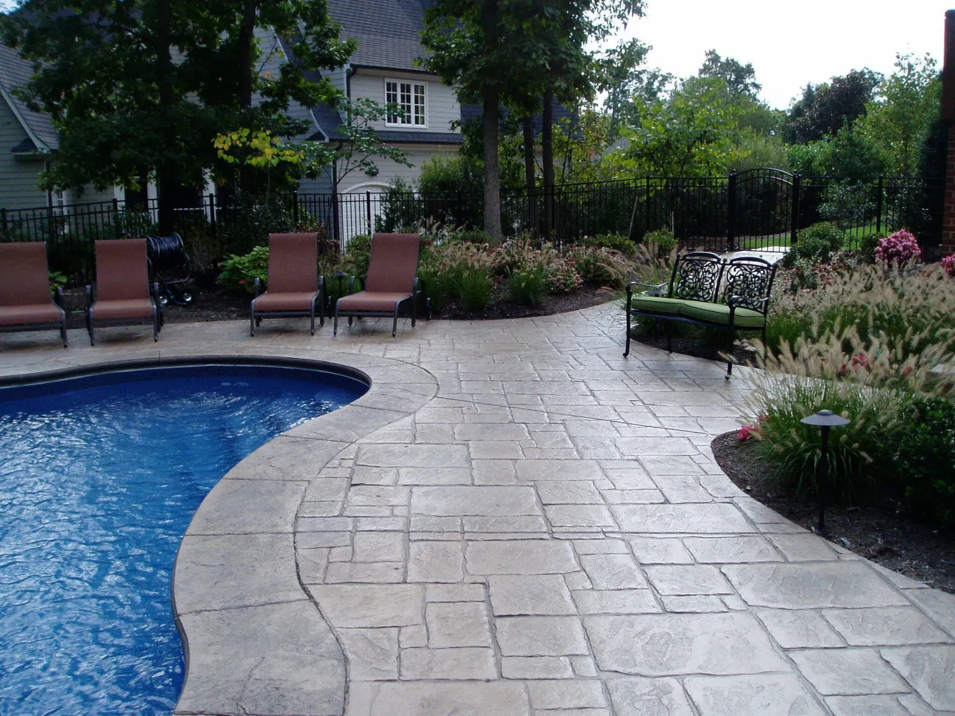 A patio with chairs and a swimming pool in the background