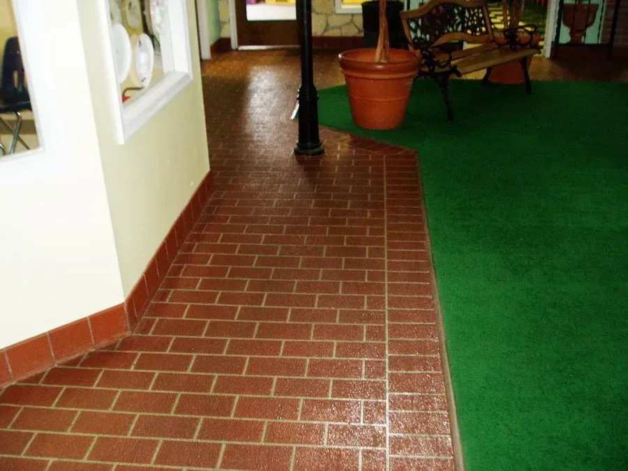 A hallway with a brick floor and green carpet