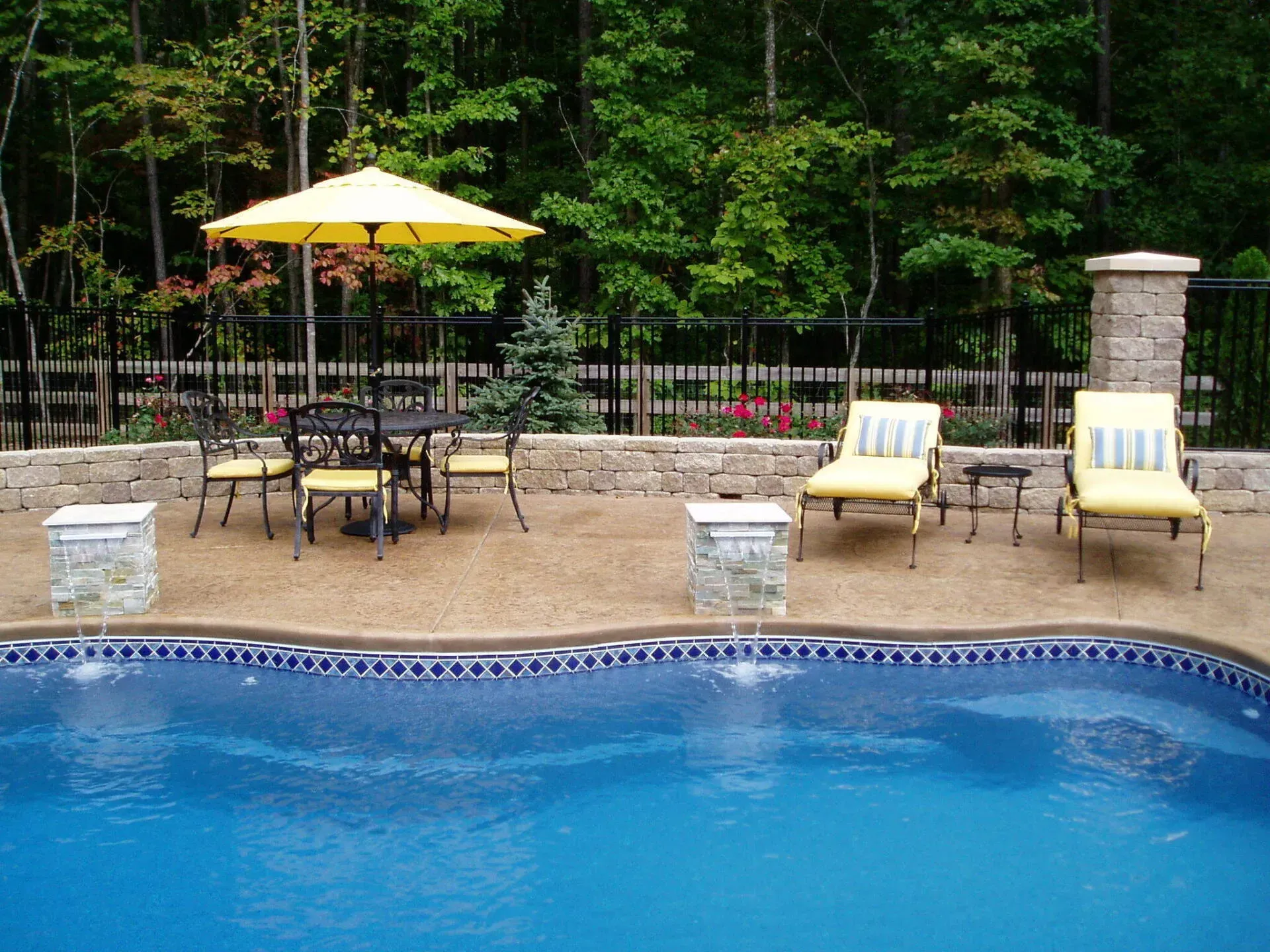 A swimming pool with a table and chairs under an umbrella